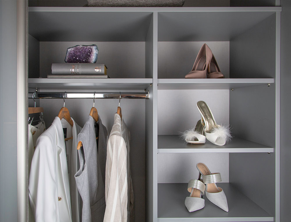 close up of shoes sitting on shelf and clothes on hanging rail